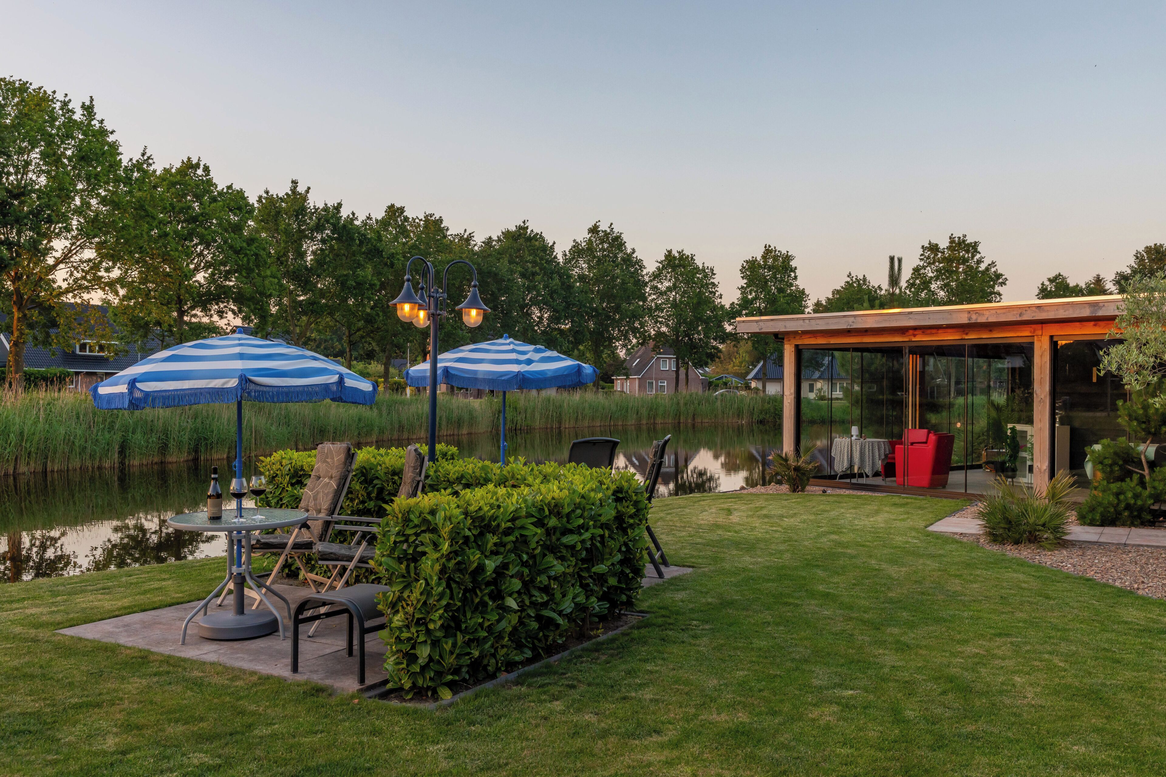 A patio with outdoor furniture, a pond, and a glass-enclosed structure.