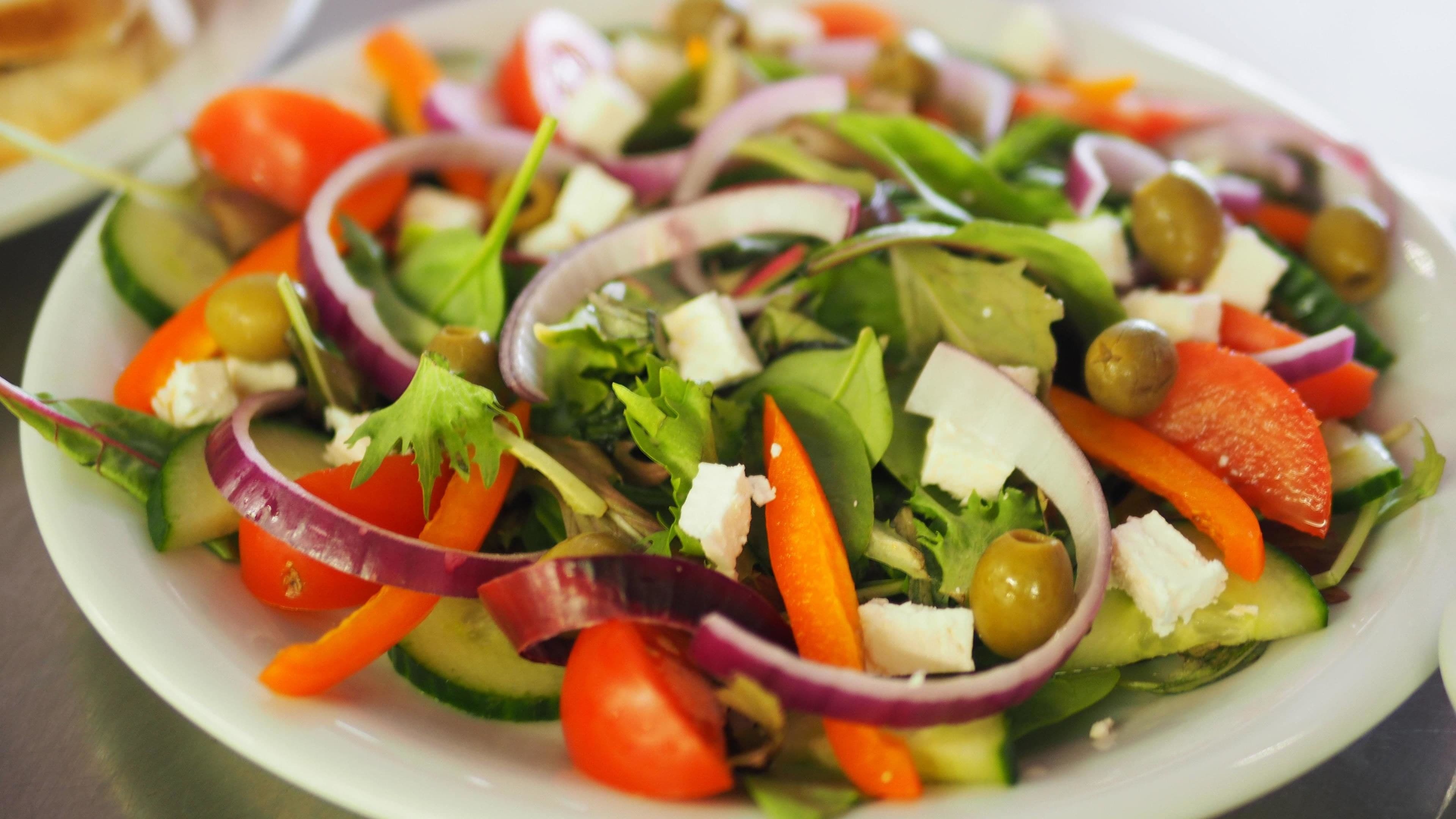 A plate of mixed salad with various vegetables and cheese.