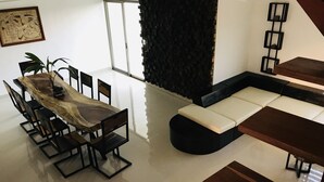 A modern living room with a dining area, featuring a wooden dining table, black chairs, a black sofa, and a black accent wall. - Apartamento 1 (Cancun)