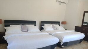 Dos camas individuales con ropa de cama blanca y cabeceros oscuros en una habitación de hotel.