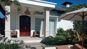 Una casa moderna con una gran puerta de madera, un porche cubierto y mobiliario exterior.