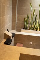 Une salle de bain moderne équipée d’une douche, d’un lavabo et d’un pot de fleurs contenant des plantes vertes.
