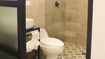 Un baño con inodoro, ducha con cerramiento de vidrio y baldosas de piso estampadas.