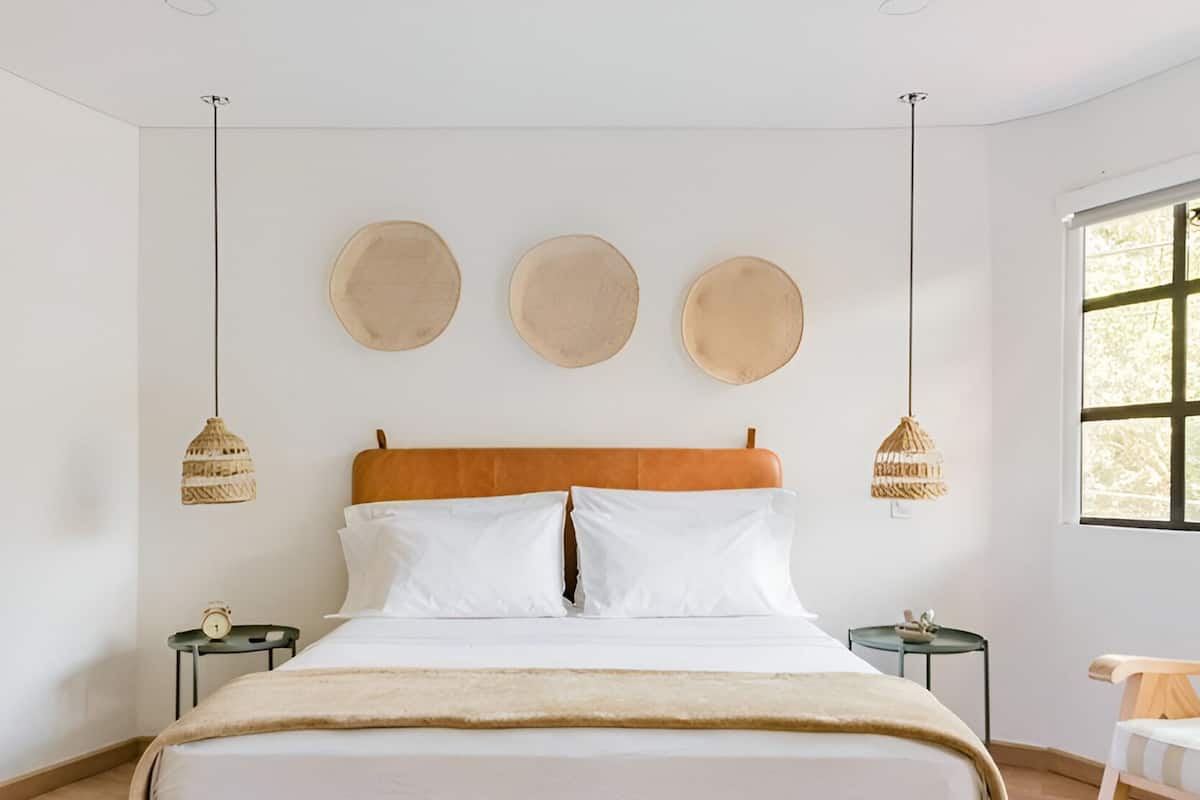 A modern bedroom with a large bed, two bedside tables, a wooden headboard, and three round wall decorations.