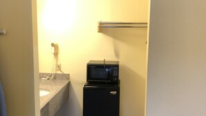 A compact kitchenette with a microwave and refrigerator, a small sink, and a towel hanging on the wall. - Inn At Mexia (Mexia)