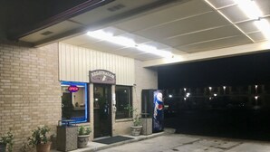 A building with a registration sign, a Pepsi vending machine, and potted plants. - Inn At Mexia (Mexia)
