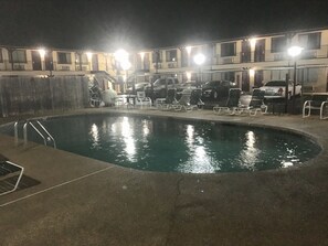A swimming pool with lounge chairs and a building in the background.