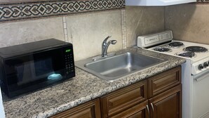 A kitchen with wooden cabinets, a microwave, a sink, and a stove. - Inn At Mexia (Mexia)