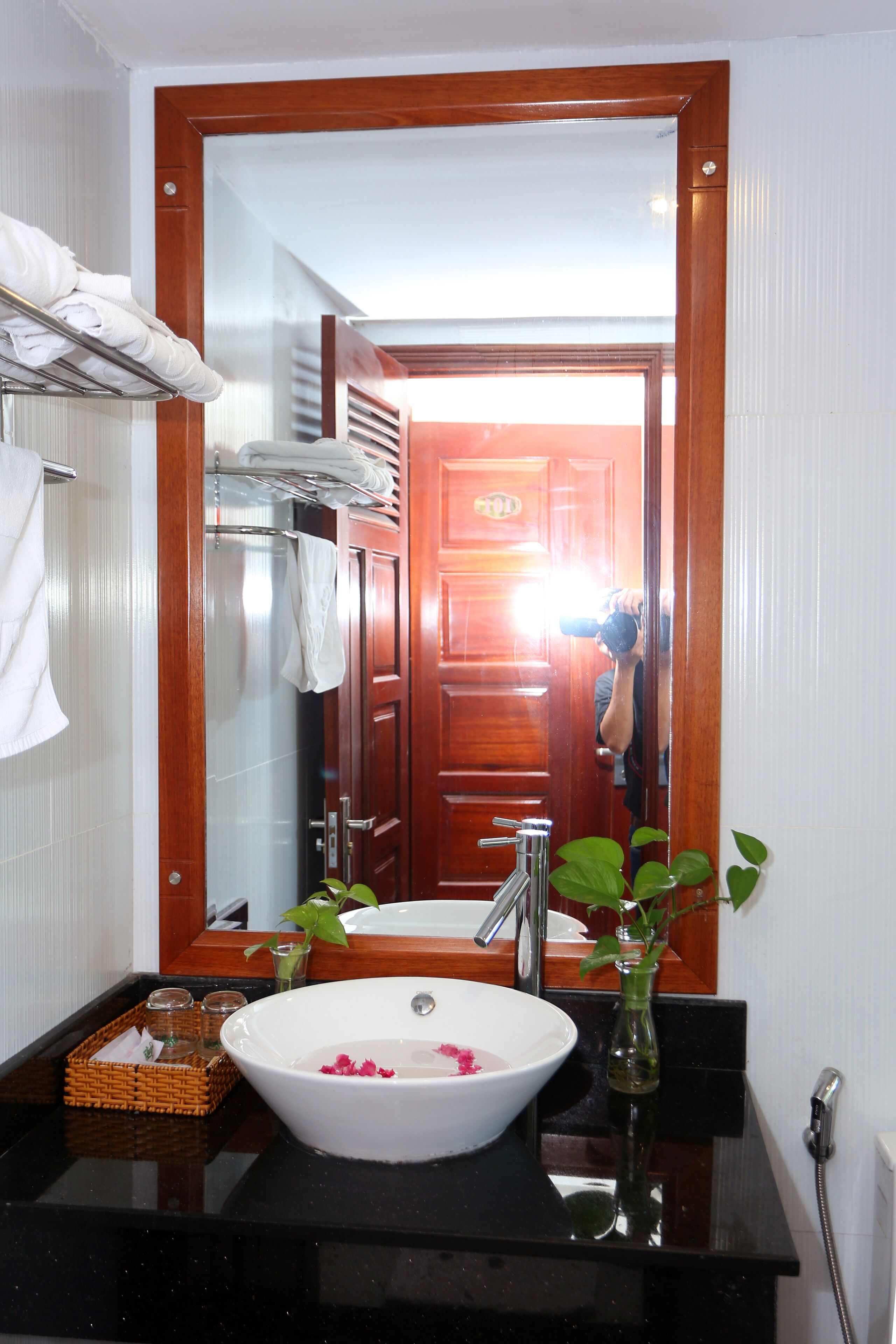 A bathroom with a white sink, a mirror, a wooden door, and a towel rack.