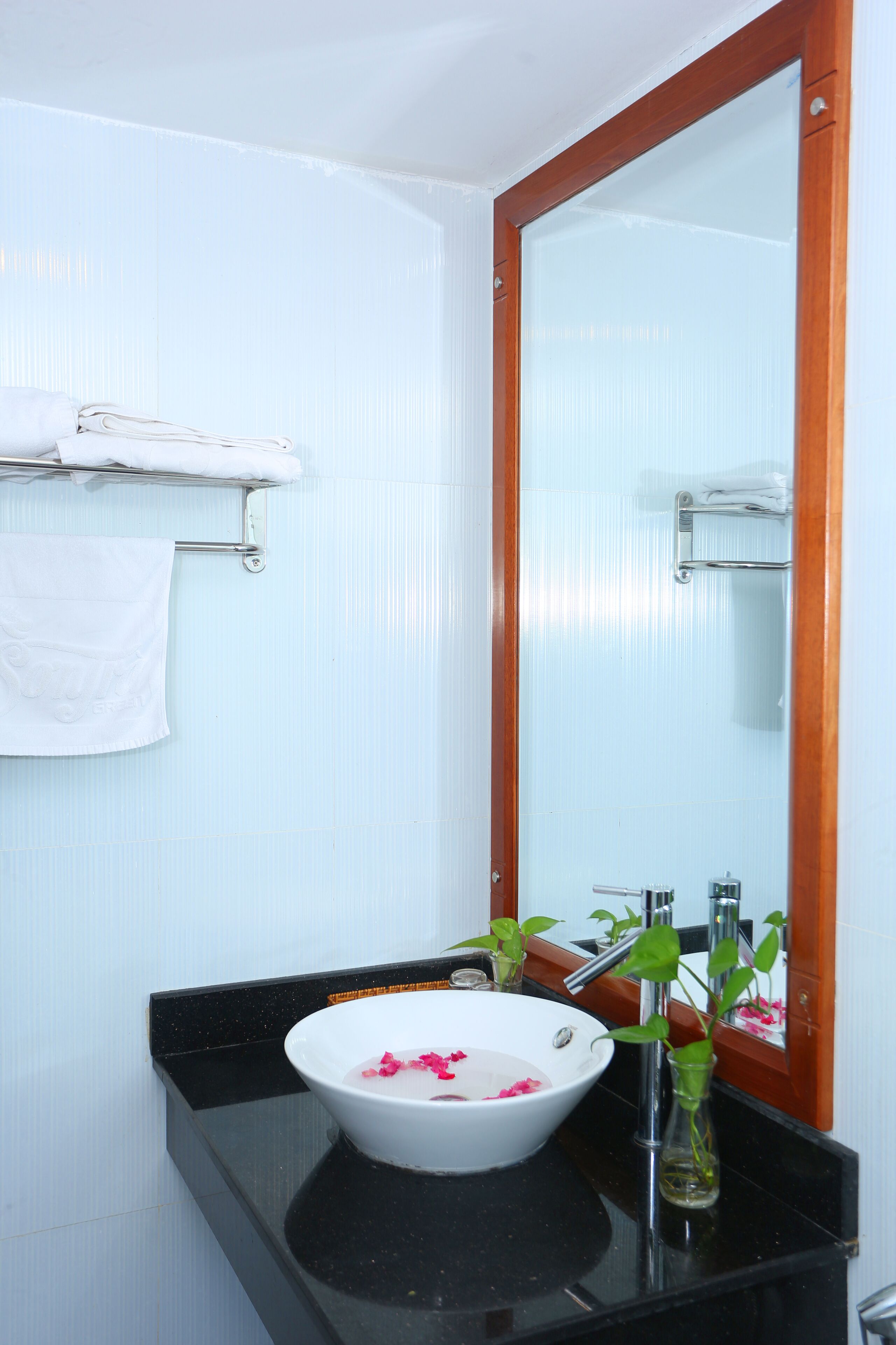 A bathroom with a white sink, black countertop, and a wooden-framed mirror.