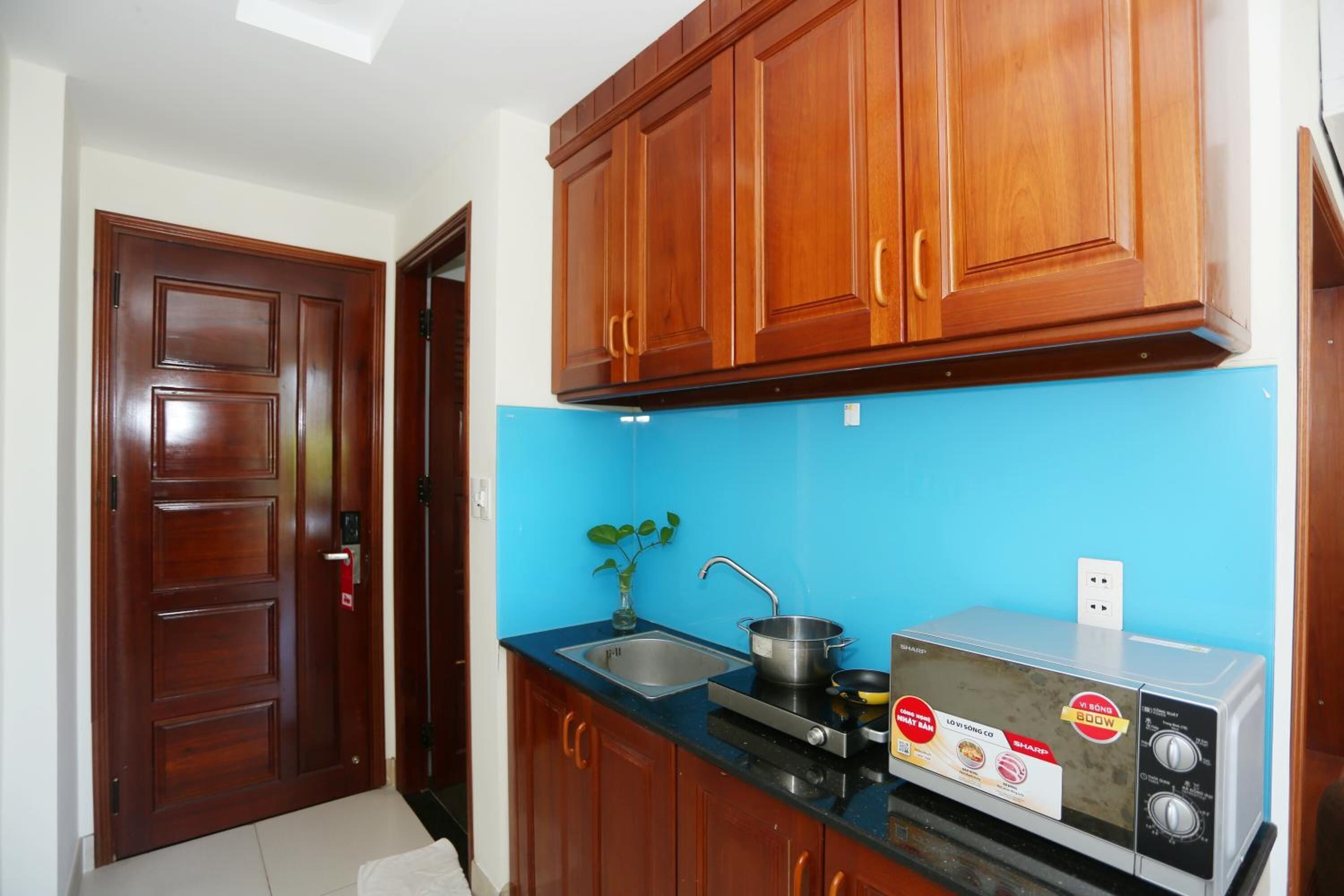 A kitchen with wooden cabinets, a blue backsplash, a sink, a stove, and a microwave.