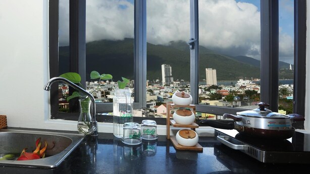Une cuisine avec vue sur la ville et les montagnes, grâce à de grandes fenêtres.
