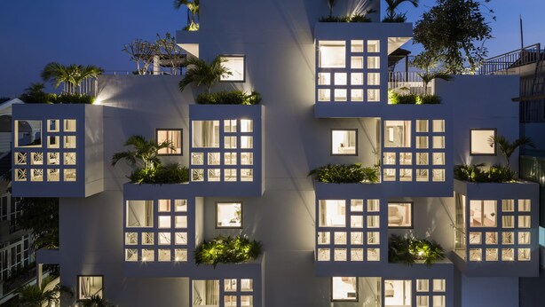 Un edificio moderno con varios balcones, cada uno con plantas y ventanas.