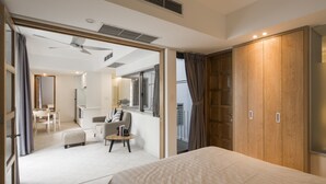 Una habitación de hotel moderna con una cama grande, un escritorio, una silla, un armario y un balcón con cortinas.