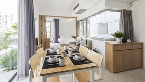 Una habitación de hotel moderna con zona de comedor, cama y vista a la ciudad.
