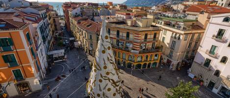 Una plaza con una gran escultura ornamentada en el centro, rodeada de edificios históricos con balcones y calles empedradas.