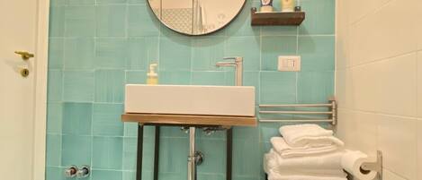 A bathroom with a sink, mirror, towel rack, and toilet.