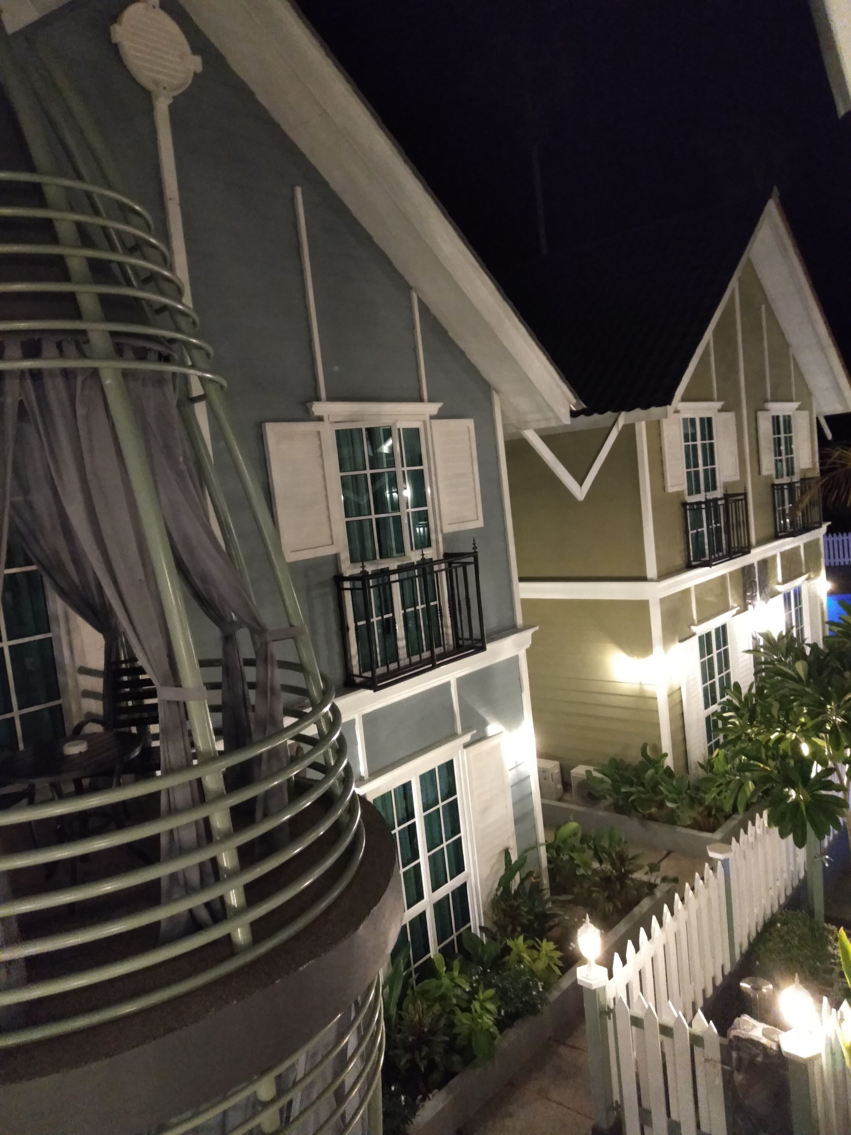 A two-story building with a balcony and a white picket fence.