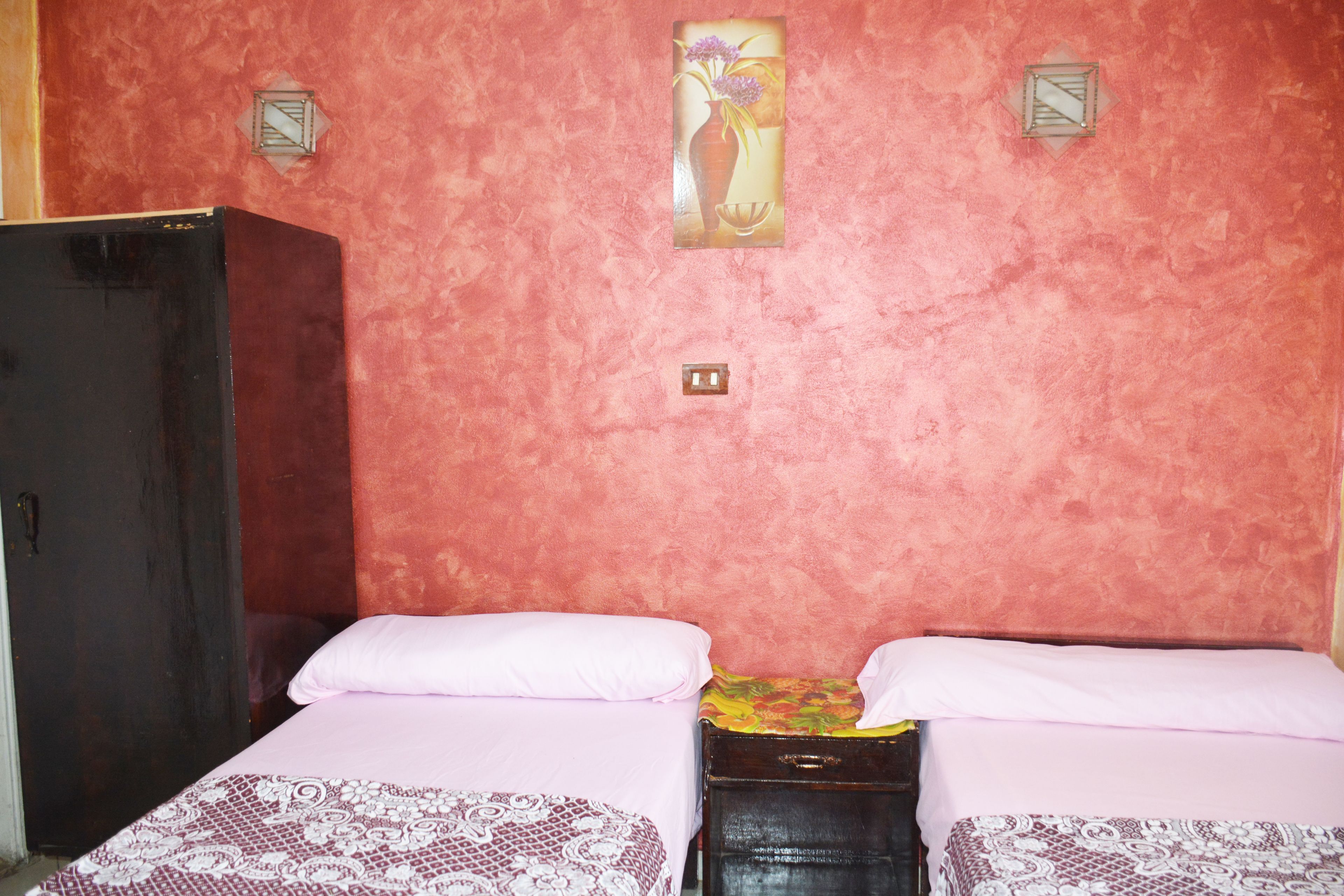Een kamer met twee bedden, een kledingkast en een lampje aan de muur.