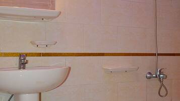 Ein Badezimmer mit Waschbecken, Spiegel, Dusche und Toilette.