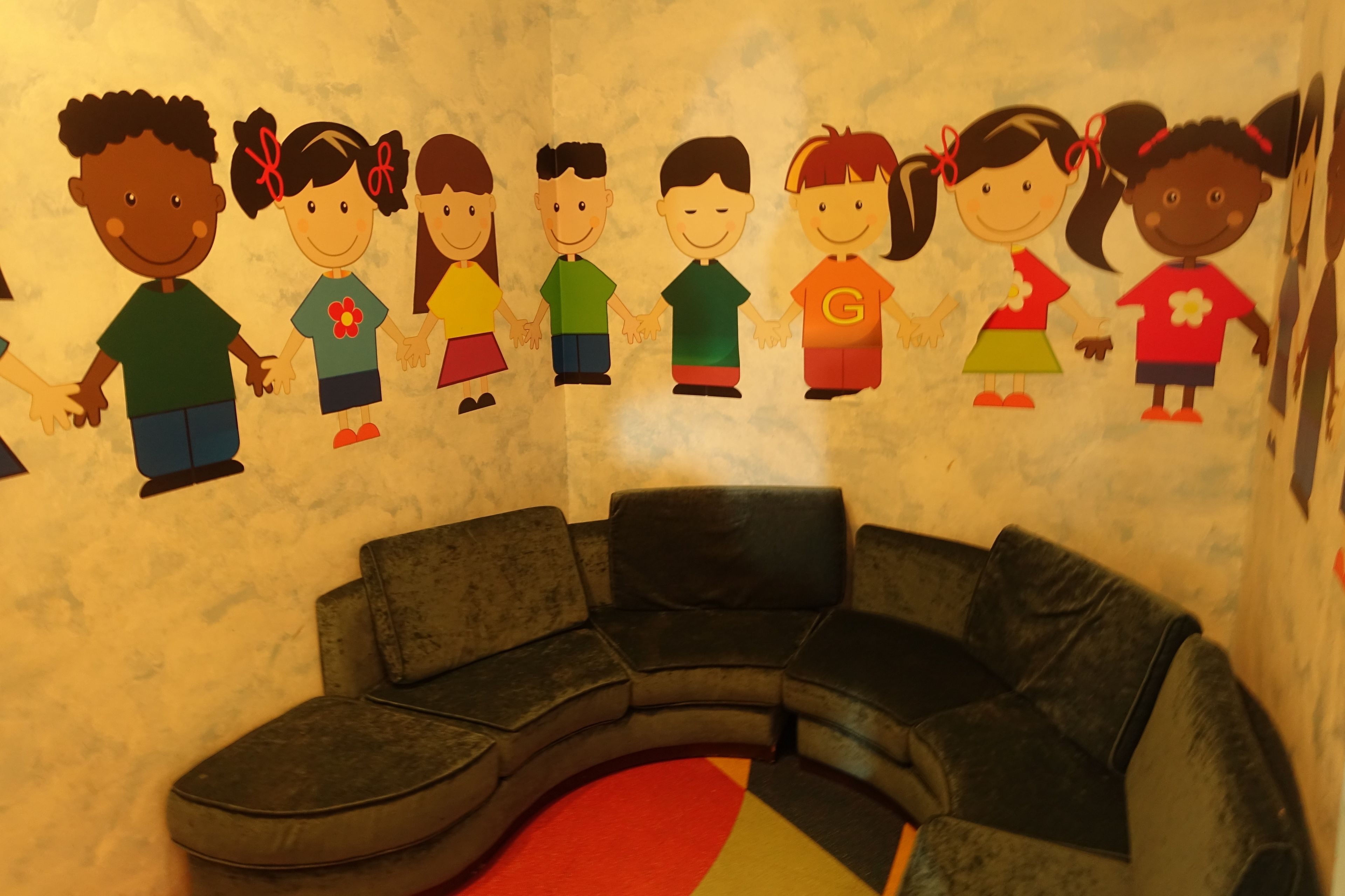 Ein Kinderspielbereich mit einer schwarzen Couch und bunten Wanddekorationen.