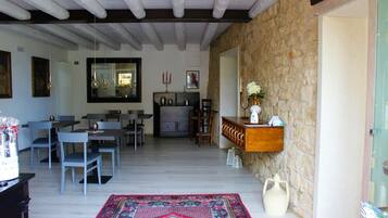 Una habitación amplia con comedor, pared de piedra y un espejo grande.