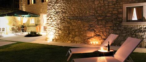 A stone building with outdoor seating and a table with a bottle and glasses.