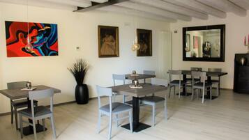 A dining area with modern furniture, a large abstract painting, and a mirror on the wall.