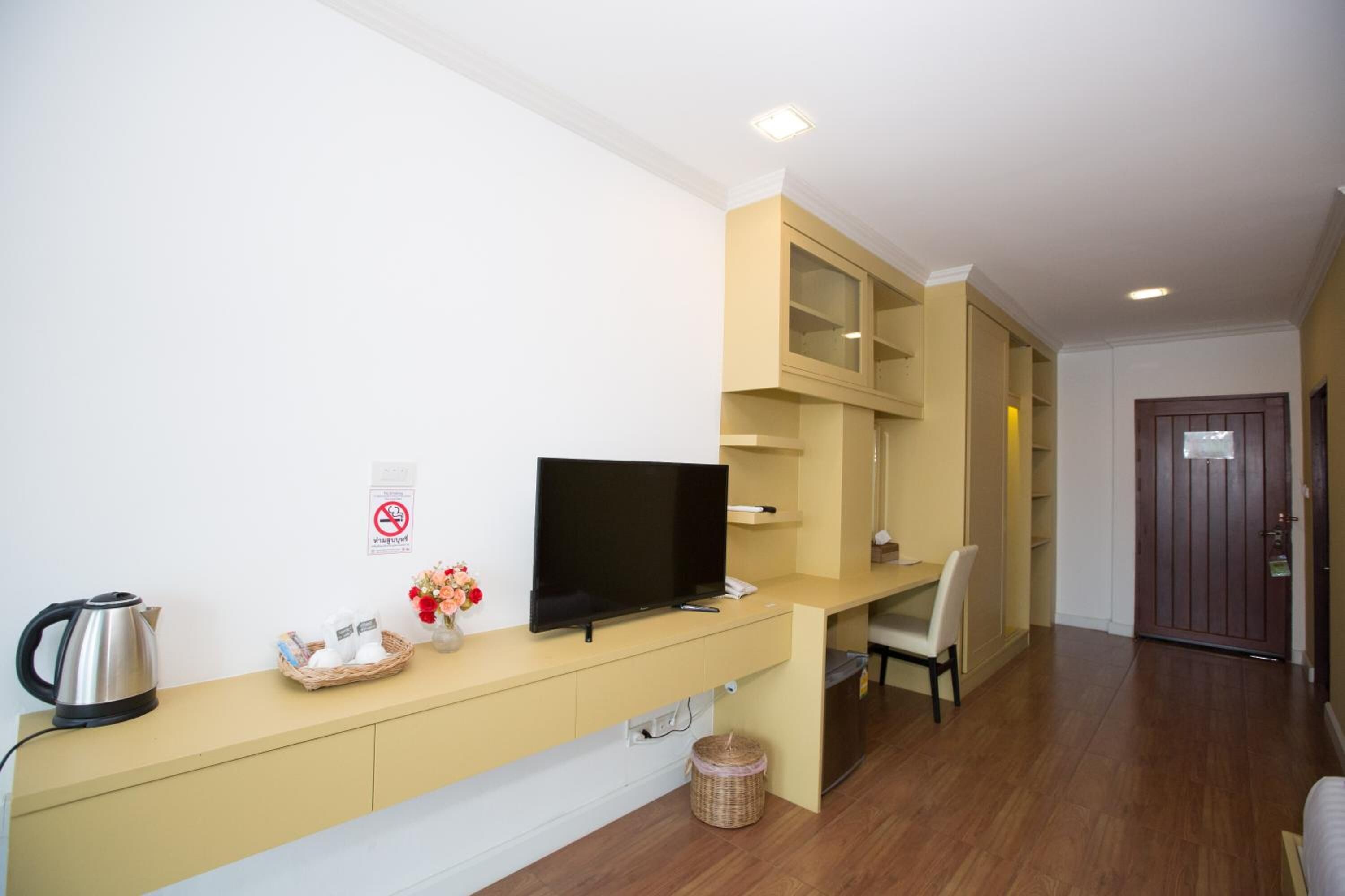 Une chambre d’hôtel moderne équipée d’une télévision à écran plat, d’une bouilloire, d’un panier contenant des articles de toilette et d’une petite table avec une chaise.