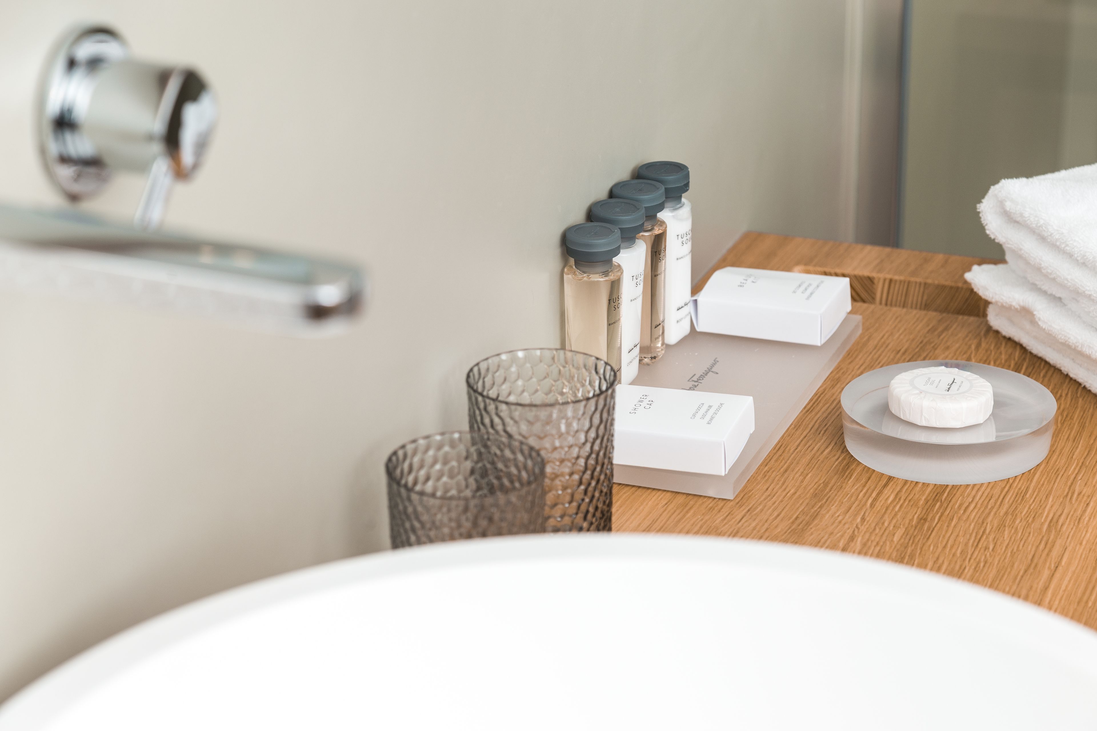 Un baño con tocador de madera, un candelabro de vidrio y una pila de toallas blancas.