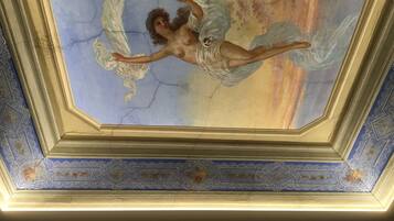 A ceiling with a fresco of a winged figure and cracked plaster.