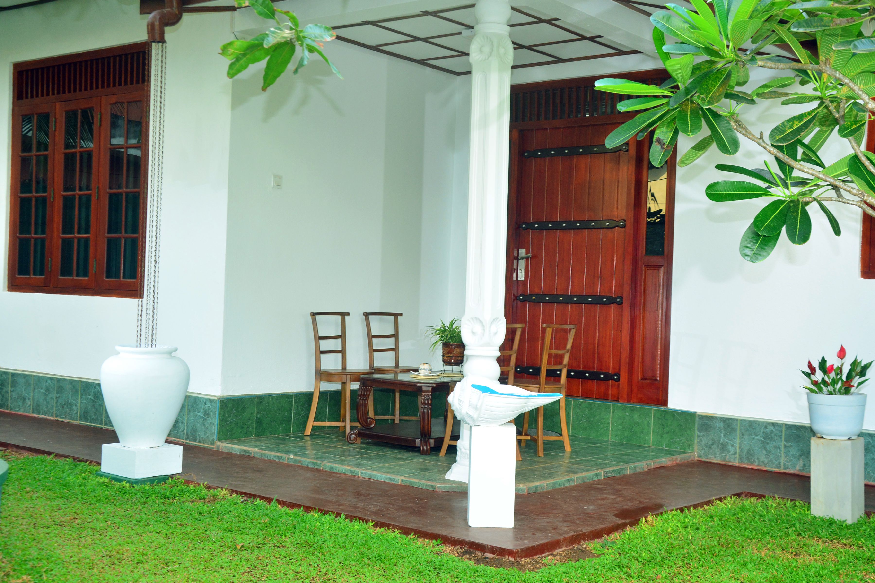 A traditional building with a wooden door, a white column, and a small table with chairs outside.
