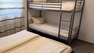 Uma cama beliche com uma cama de baixo e uma cama de solteiro, ambas com roupa de cama branca.