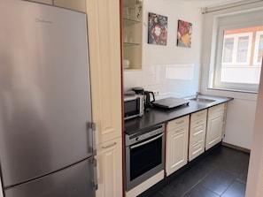 A modern kitchen with a built-in refrigerator, oven, microwave, and a coffee maker on the countertop. - Hilda Apartments Rust (Rust)