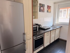 A modern kitchen with a built-in refrigerator, oven, microwave, and a coffee maker on the countertop.