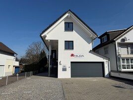 A two-story building with a garage door, a sign for Hilda apartments, and a clear sky.