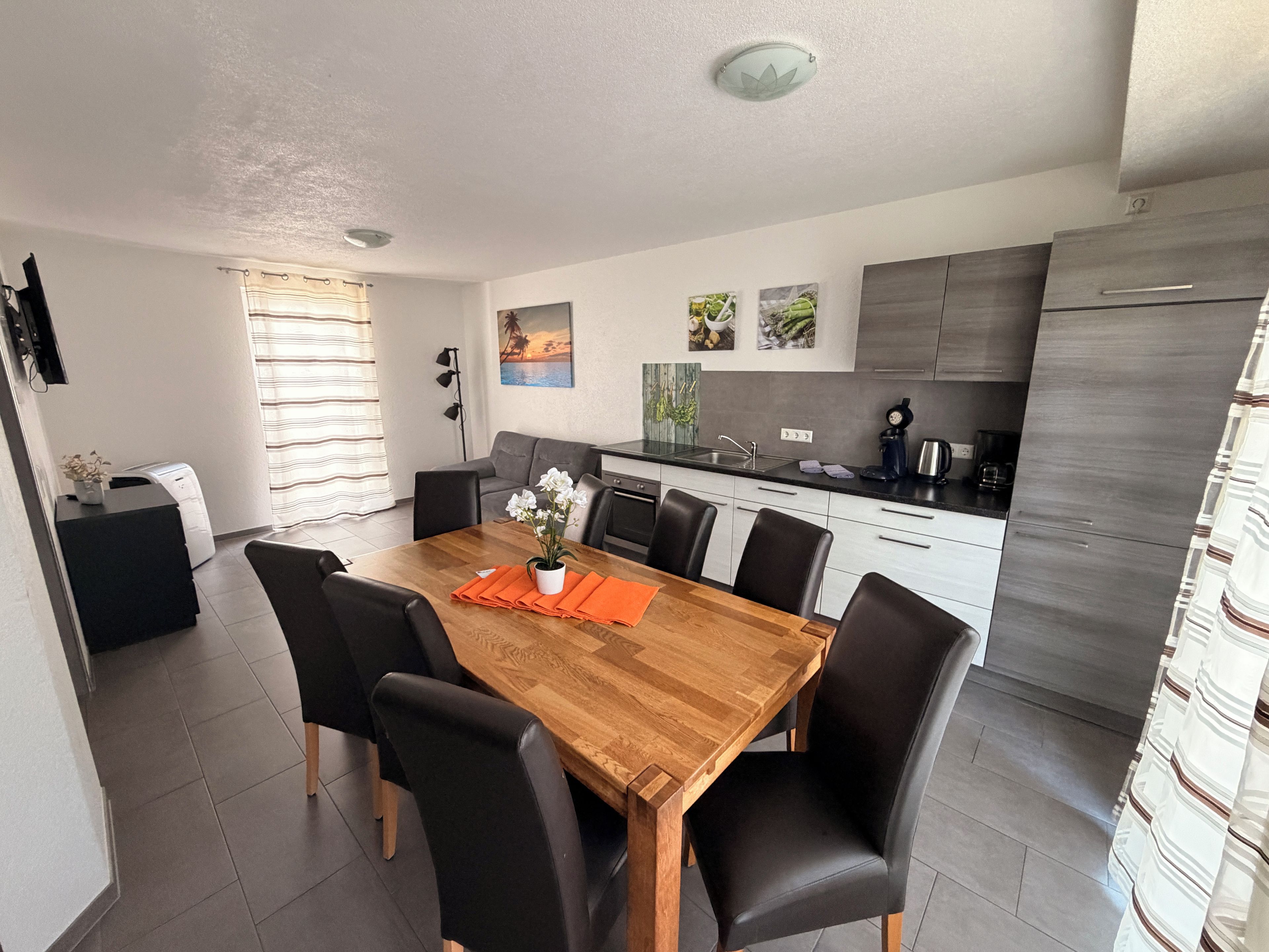 Una cocina moderna con una mesa de comedor de madera, sillas negras y una cafetera.