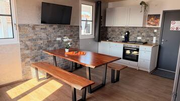 Una cocina moderna con una mesa de madera, banco, salpicadero de piedra y televisor de pantalla plana.