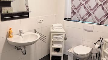A modern bathroom with a white sink, toilet, and a towel rack.