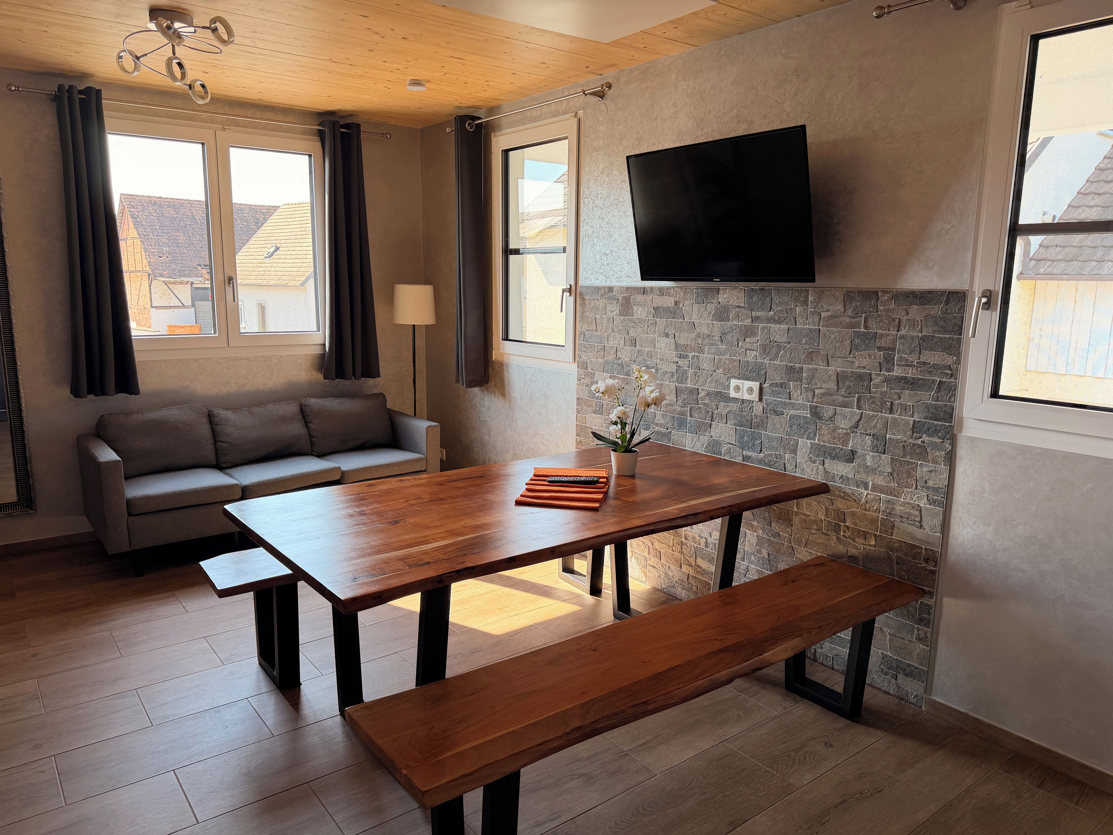 Una sala moderna con un sofá, una mesa de comedor de madera y una pared de acento de piedra.