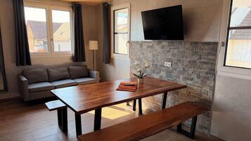 Una sala moderna con un sofá, una mesa de comedor de madera y una pared de acento de piedra.