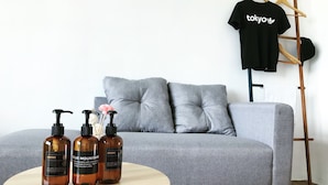 A grey sofa, a round wooden table with three brown bottles, and a black t-shirt with "Tokyo" on it. - Studio near IKEA & Aeon Tebrau City (Johor Bahru)