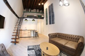 A loft-style living space with a staircase, a kitchen area, and a seating area with a sofa and a coffee table. - The Dante House (Naples)