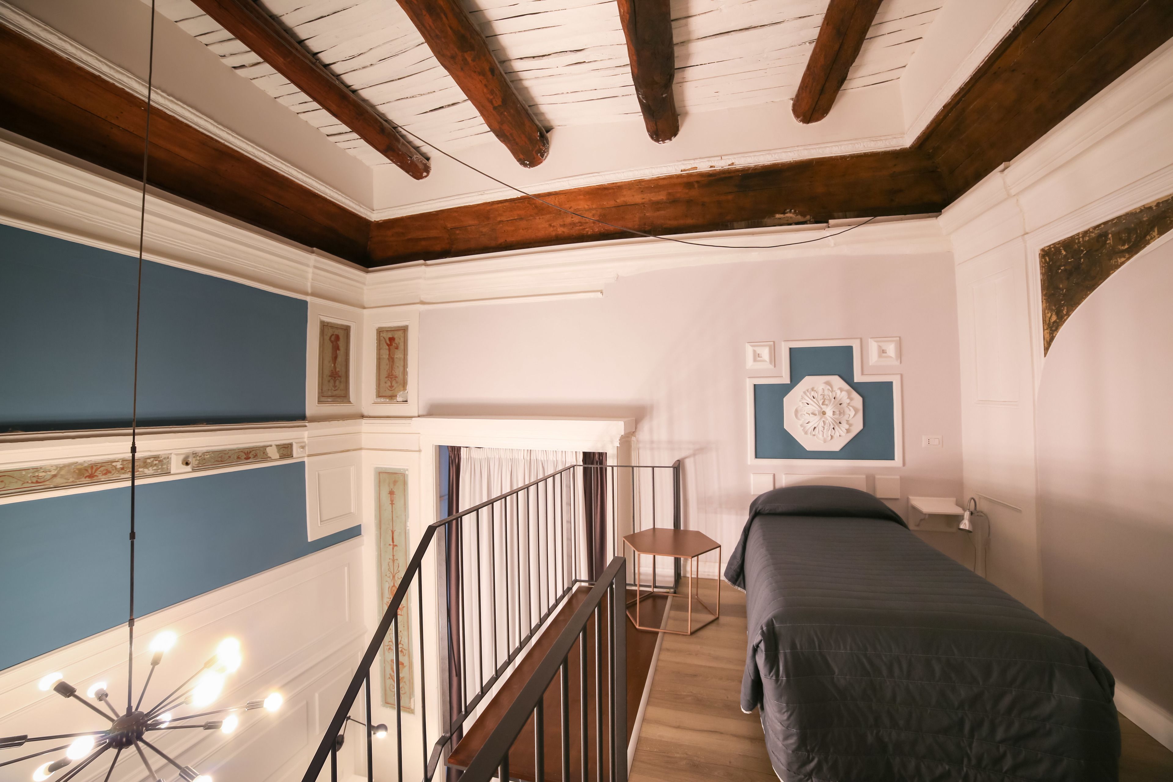 Una habitació amb sostre de fusta, un llit, una taula petita i una paret amb un element decoratiu.