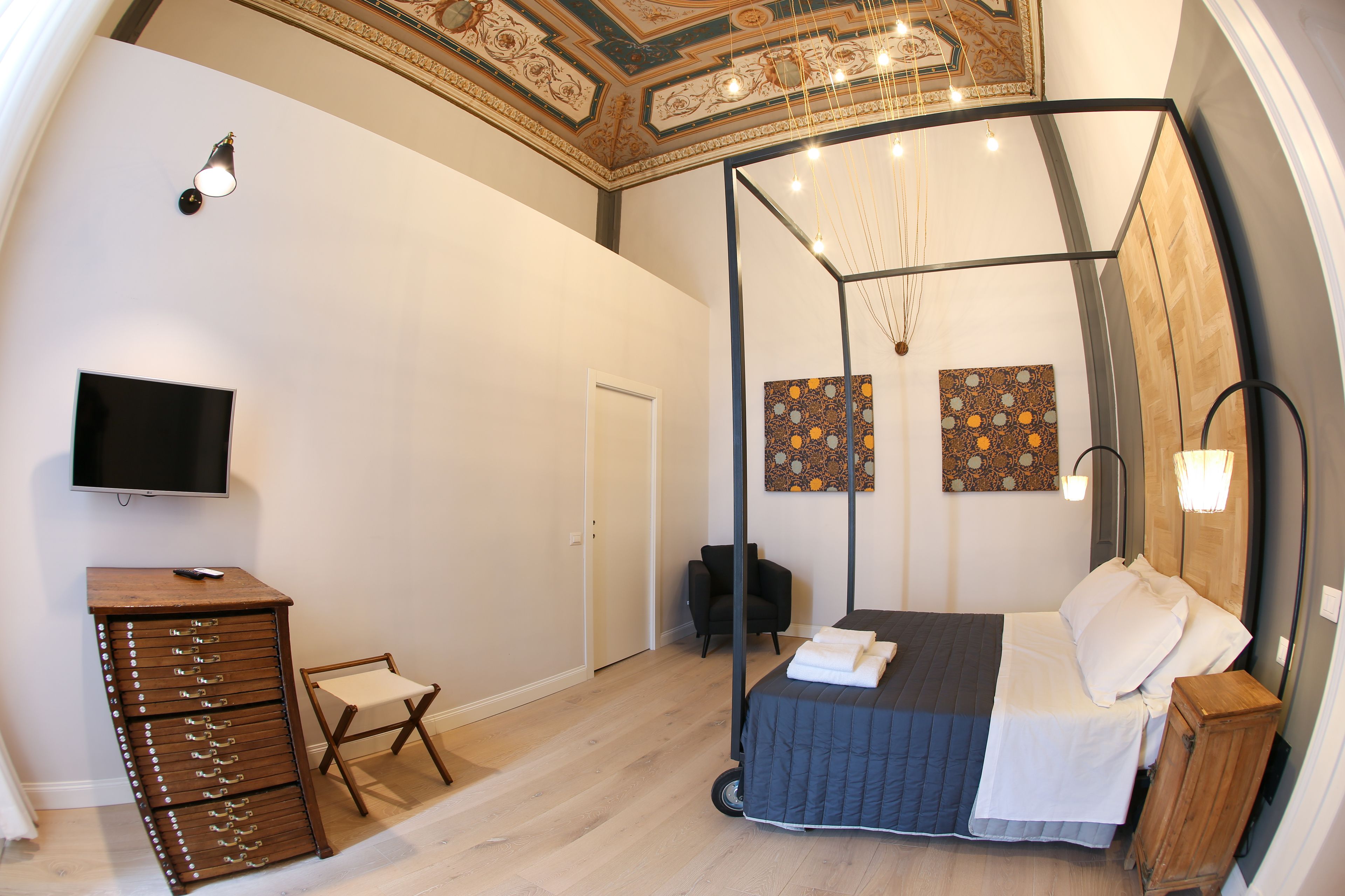 A bedroom with a bed, a TV, a dresser, and artwork on the walls.