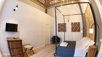 A bedroom with a bed, a TV, a dresser, and artwork on the walls.