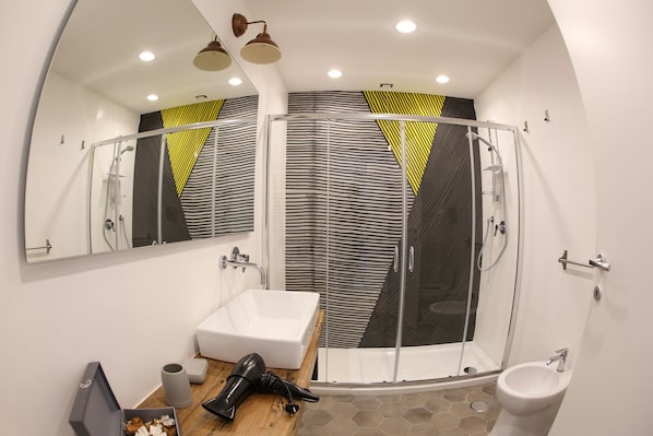 A modern bathroom with a glass shower enclosure, a white sink, and a bidet. - The Dante House (Naples)