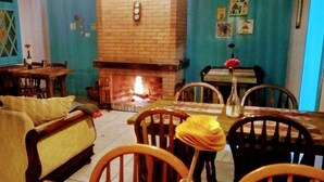 A cozy living room with a fireplace, wooden furniture, and a blue accent wall. - Pousada Casa João e Maria II (Gramado)