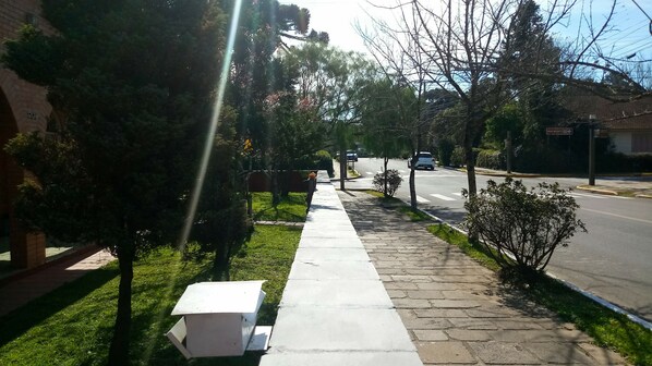 A residential street with a sidewalk, houses, and a road. - Pousada Casa João e Maria II (Gramado)