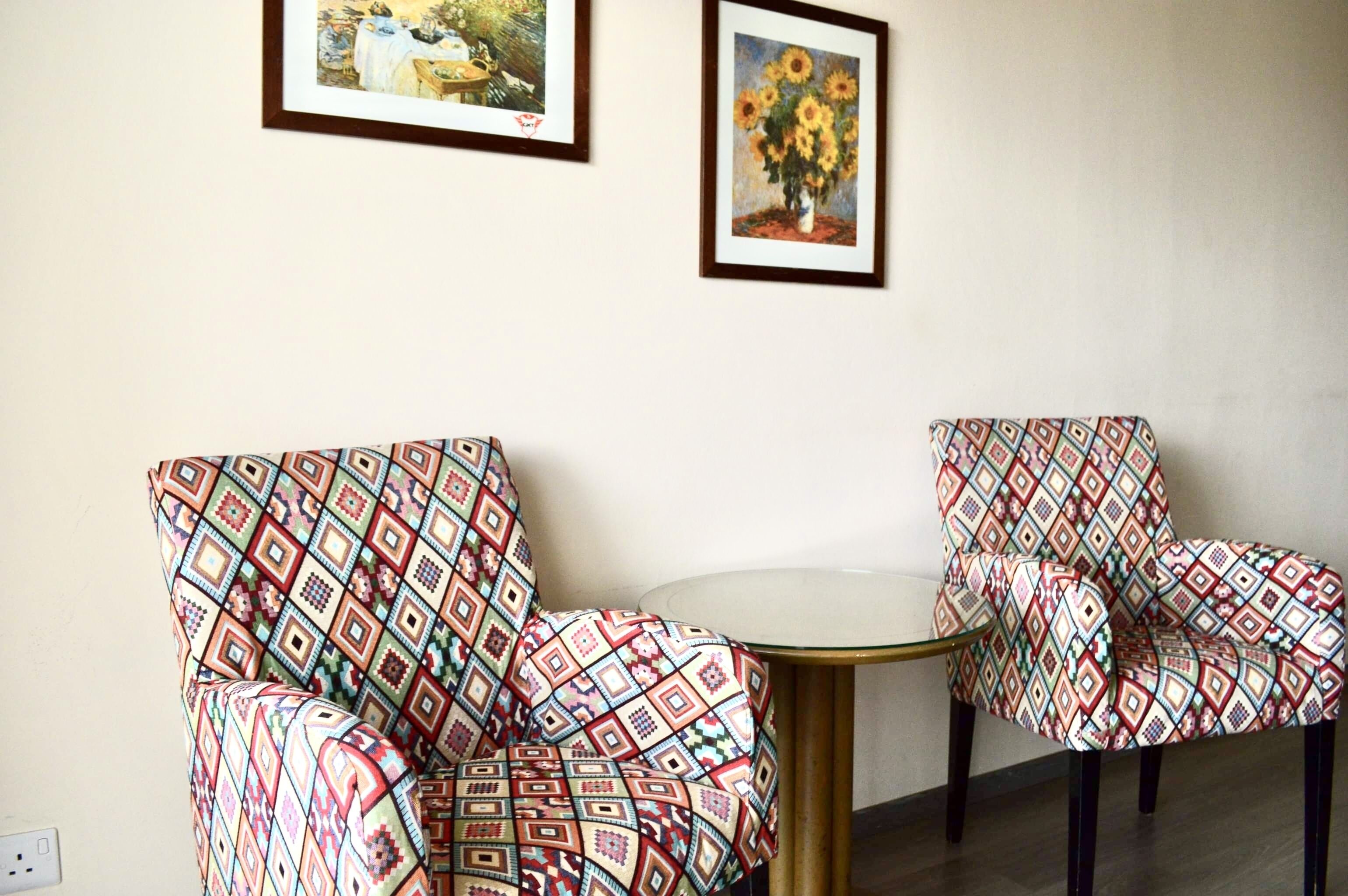 Una habitación con dos sillones estampados y una mesita redonda.